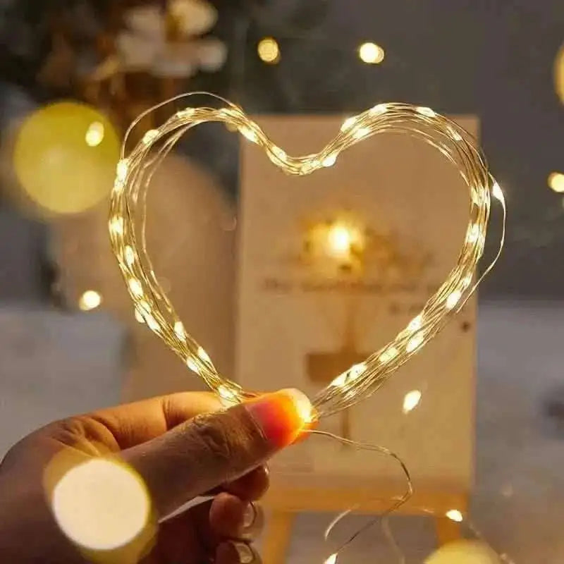 Warm white LED string lights shaped like a heart, glowing on copper wire.