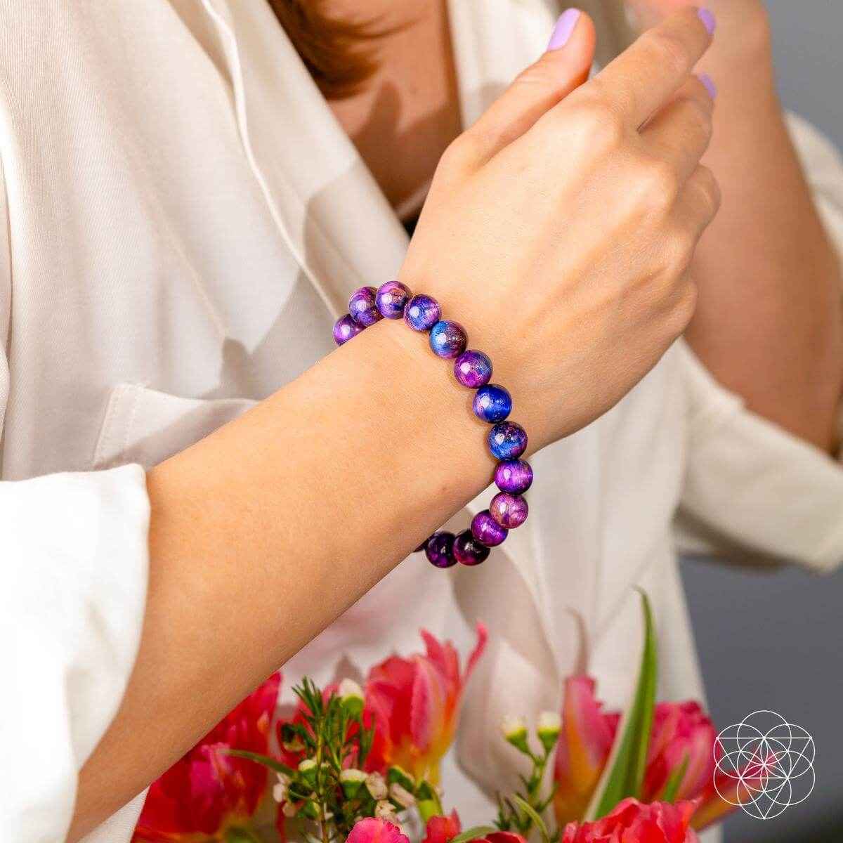 Purple and blue beaded bracelet worn on a wrist with round stone beads