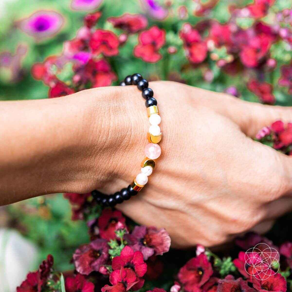 Shungite bracelet on wrist with black bead strand and pink and gold bead spacers