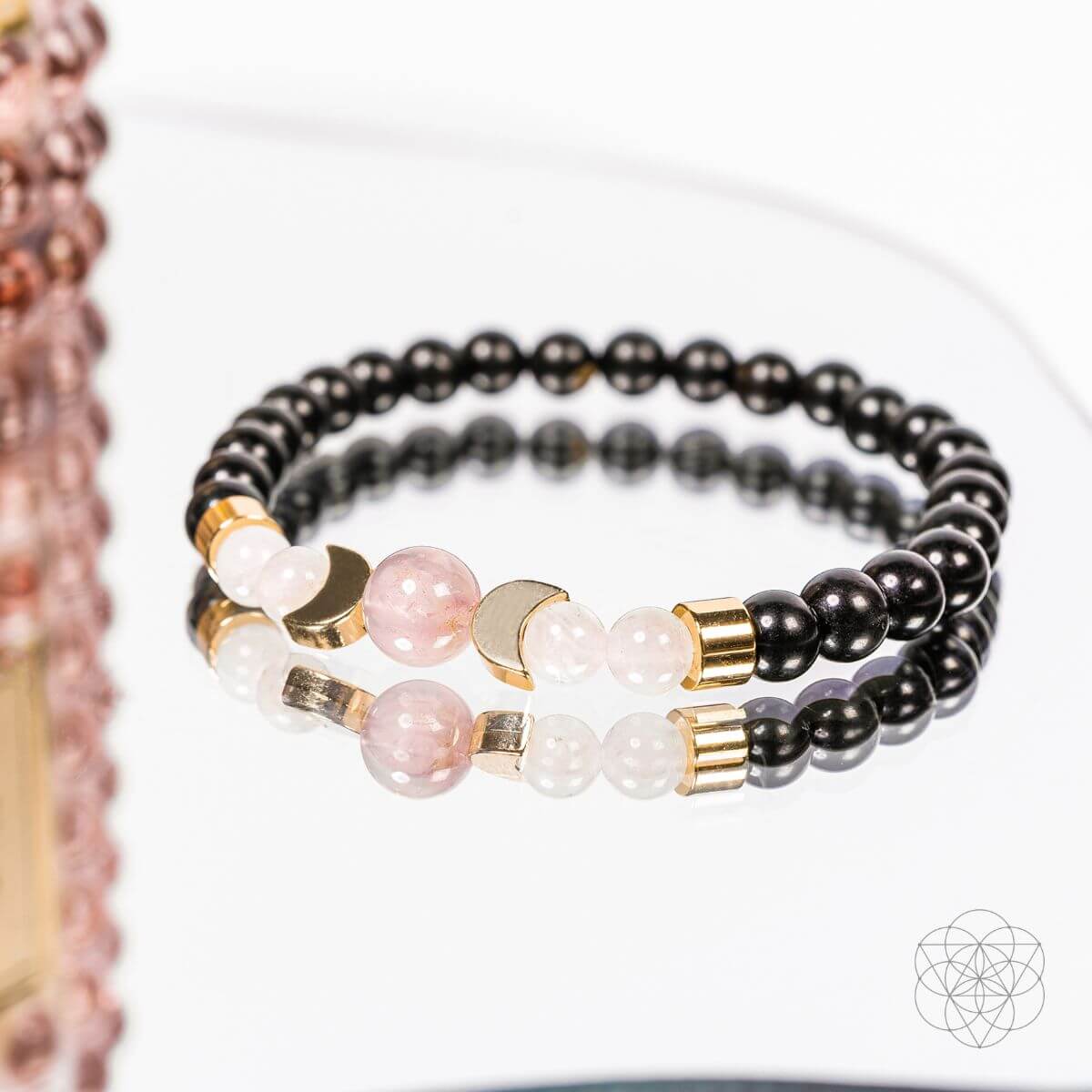 Shungite supercharged bracelet close-up with black beads, pink stones, and gold accents