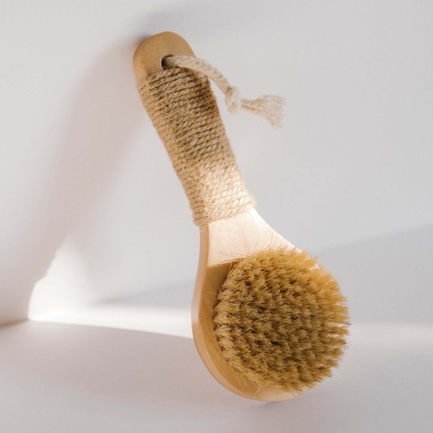 Dry body brush with oval wood handle, hemp-wrapped grip, and round natural bristle head