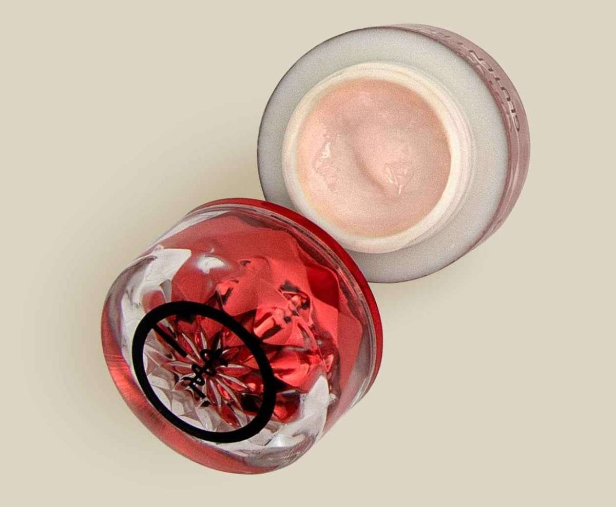 Eye cream jars, one clear with red base and one white with pink cream