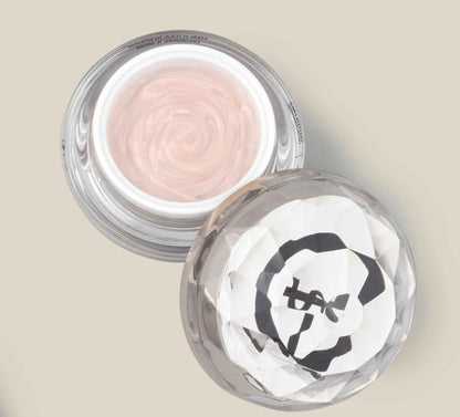 Face cream jar with pale pink cream and faceted clear lid