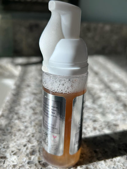 Close-up of foaming facial cleanser bottle with white pump and froth