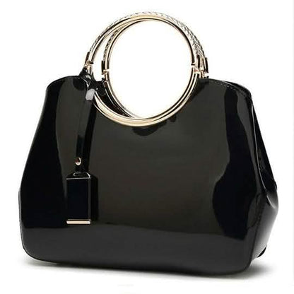 Black handbag with gold ring handles and hanging charm tag