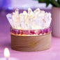 Quartz and tourmaline crystal lamp with clear crystal cluster and wooden base, lit glow