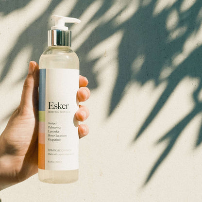 Firming body wash bottle held in hand, clear liquid and silver pump top