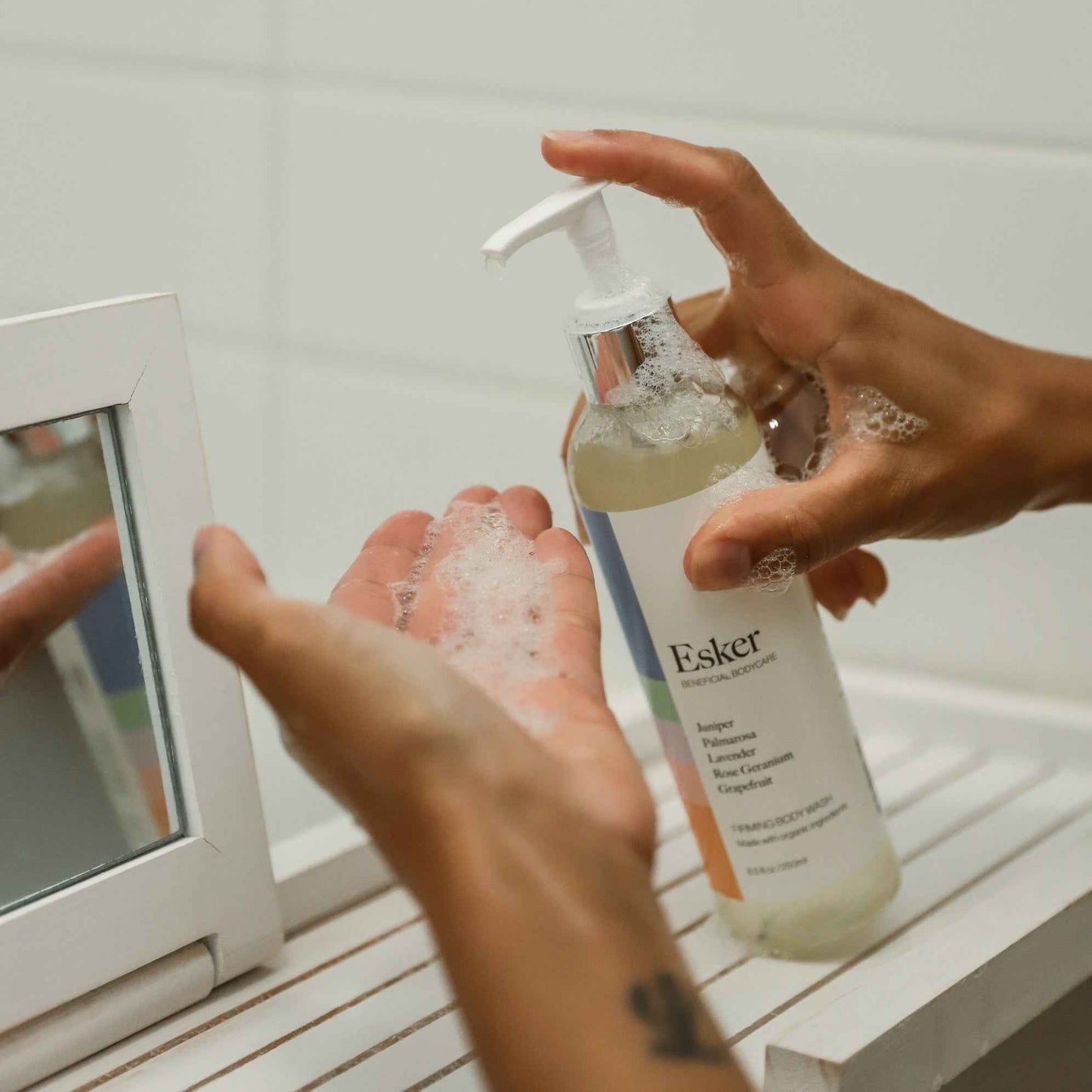 Esker body wash pump bottle being applied onto hands under running water