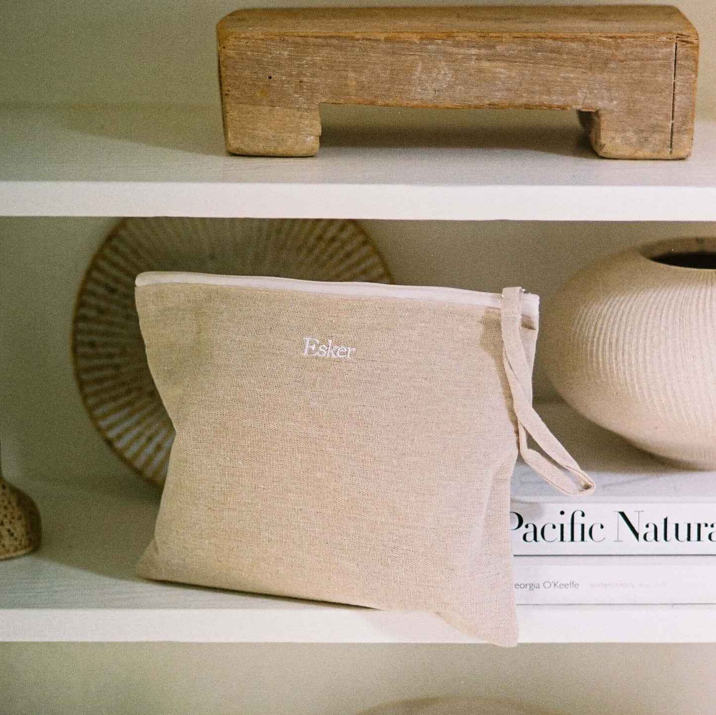 Linen pouch with knotted cord on shelf, with Esker oil products nearby