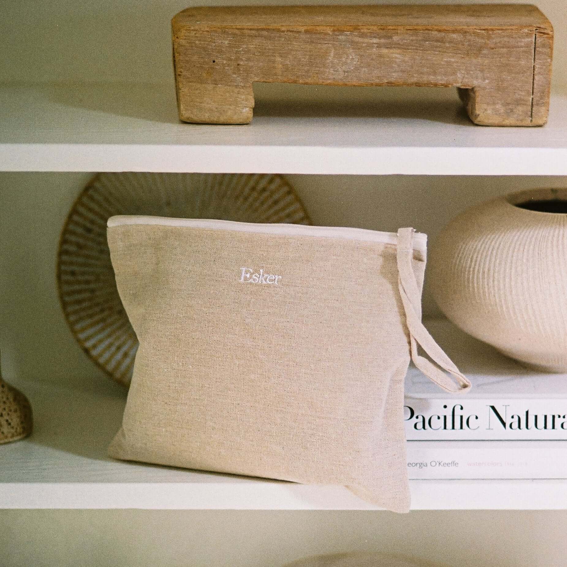 Linen pouch with knotted cord on shelf, with Esker oil products nearby
