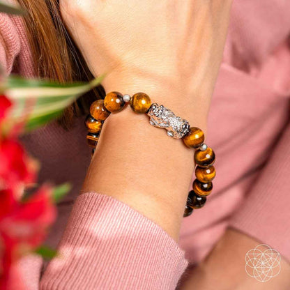 Tiger’s eye bead bracelet with silver Pixiu charm on a wrist
