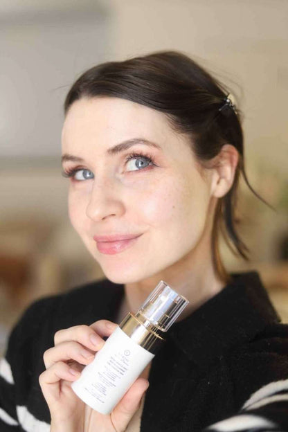 Woman holding EpiLynx gentle exfoliating face scrub bottle with gold pump