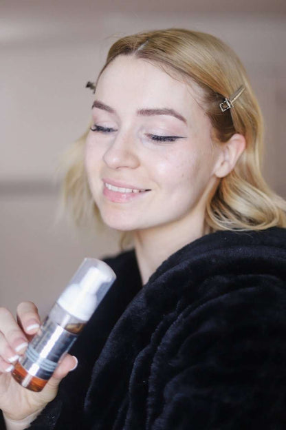 Gentle foaming facial cleanser bottle with white pump, held near cheek