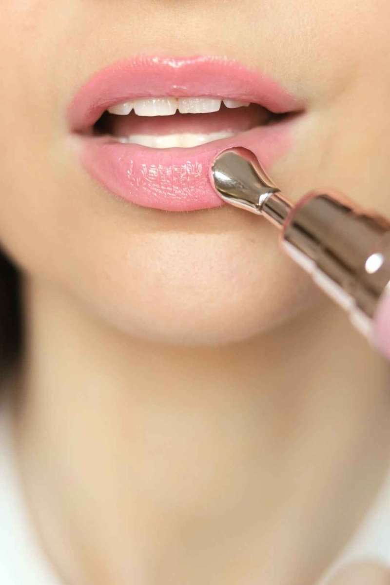 Glossy pink lip treatment being applied with metal applicator tip on lips