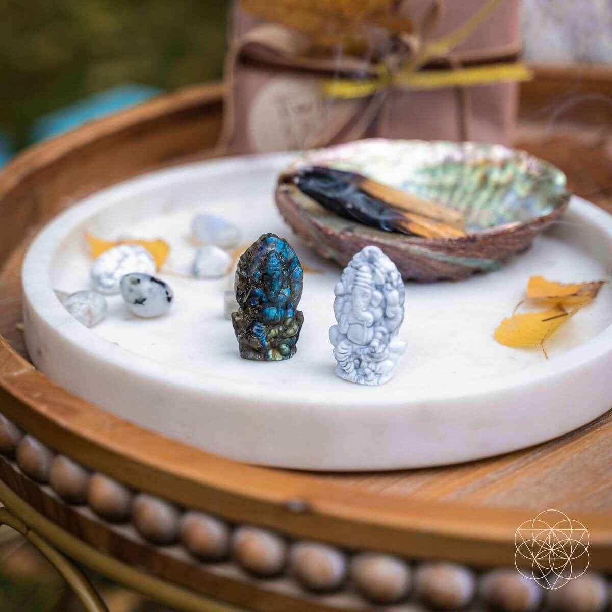 Crystal Ganesh statues on a white tray: dark blue labradorite and white howlite