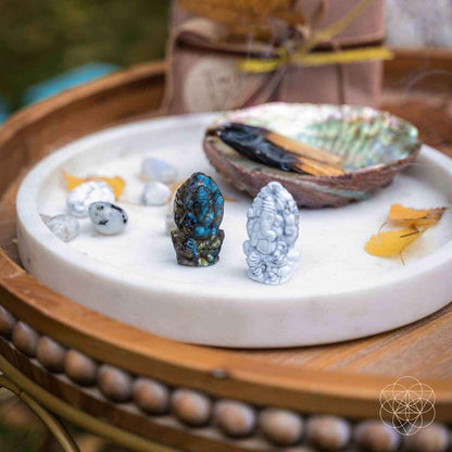 Crystal Ganesh statues on a white tray: dark blue labradorite and white howlite