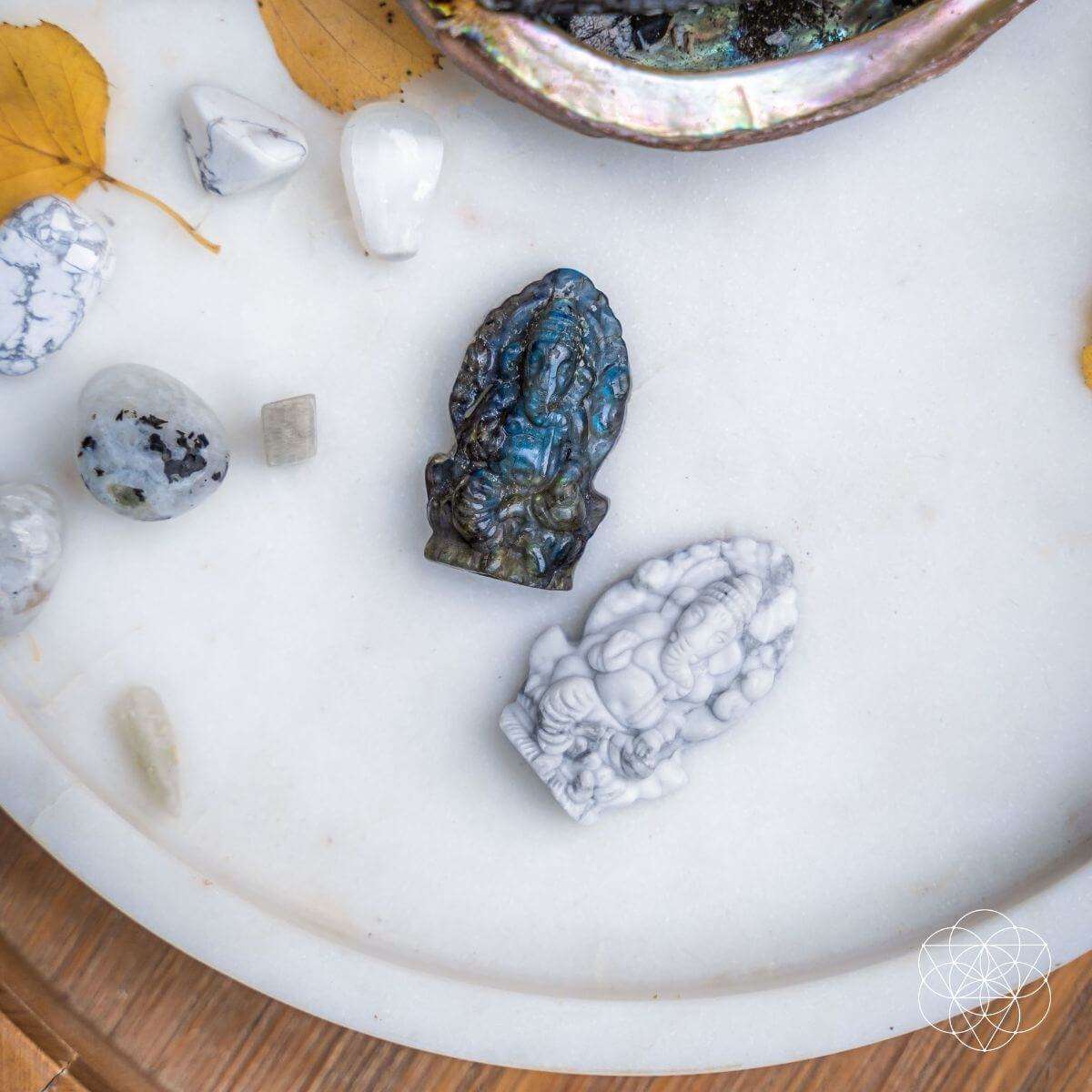 Close-up of crystal Ganesh statues on a white dish: dark blue and white pieces