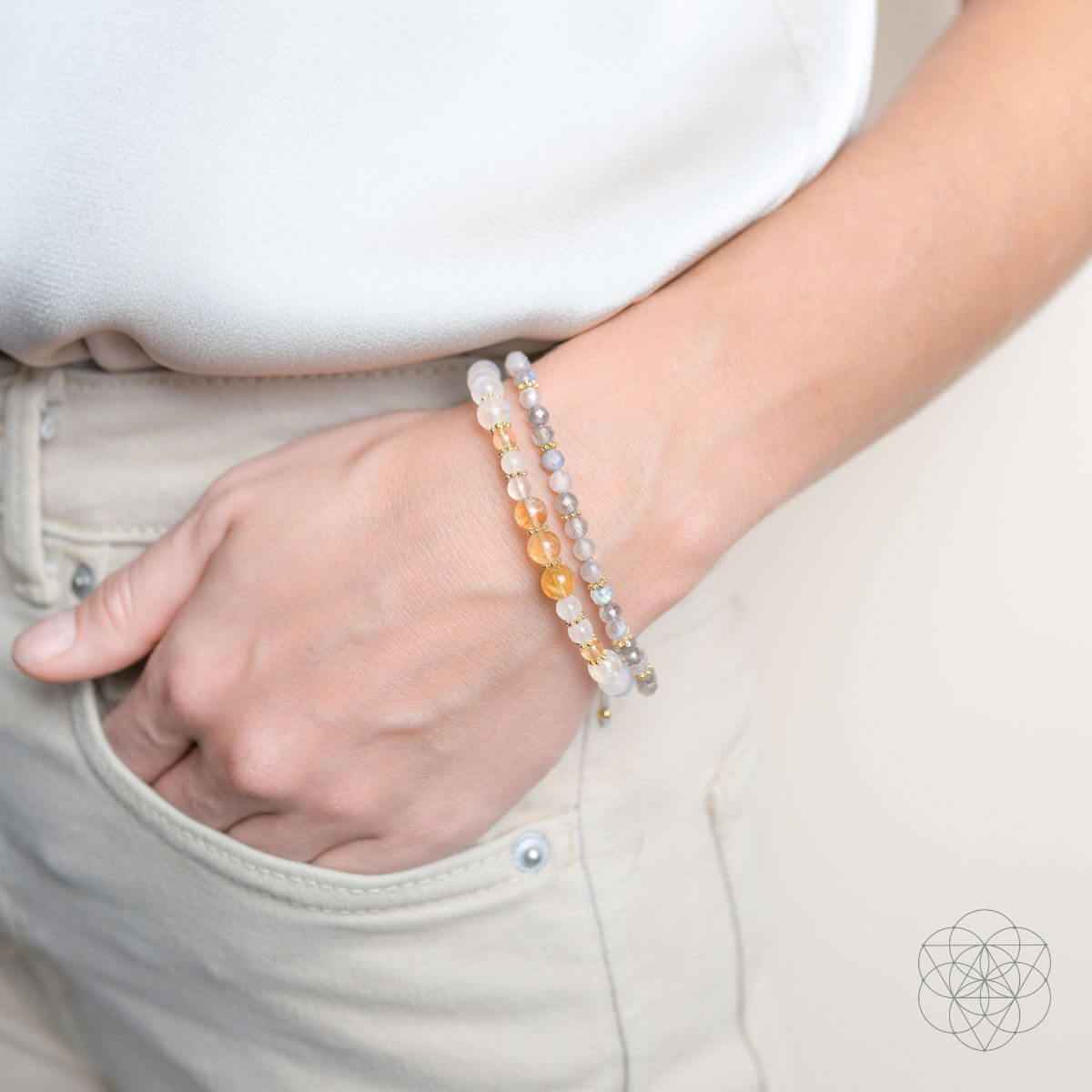 Layered bead bracelets on wrist with white and gold-toned beads