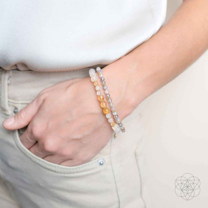 Layered bead bracelets on wrist with white and gold-toned beads