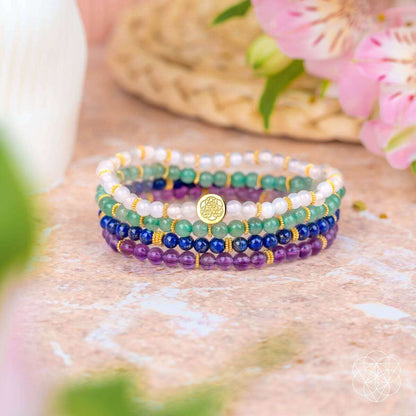 Four beaded bracelets with gold charm on light stone, blue, green, purple and white beads