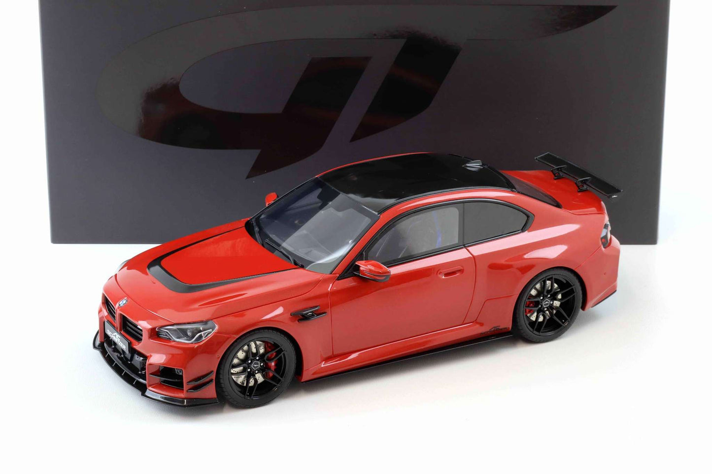 Red die-cast sports car model with black wheels and front grille, 3/4 view