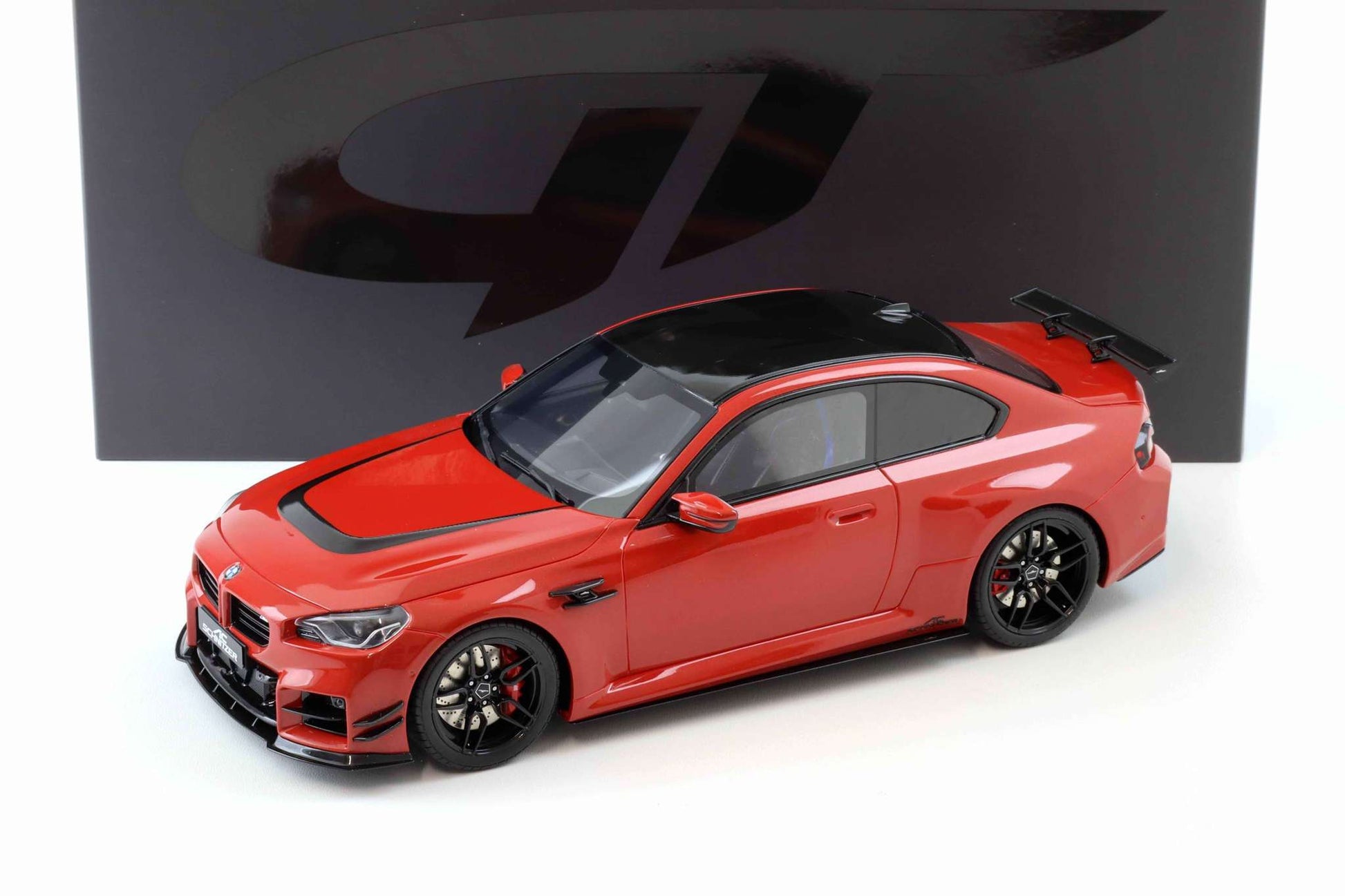 Red die-cast sports car model with black wheels and front grille, 3/4 view