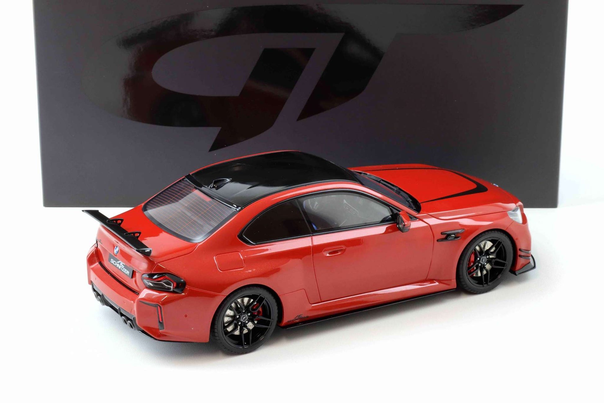 Red die-cast sports car model with black wheels and rear spoiler, 3/4 view