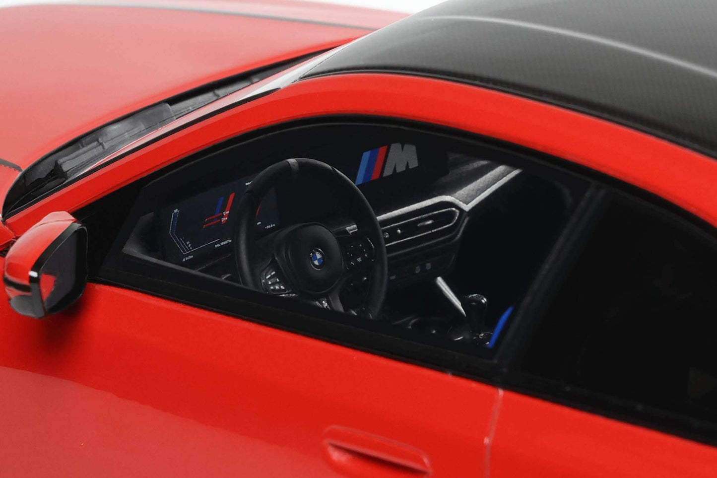 Die-cast car interior close-up with black dashboard, steering wheel, and blue M stripe