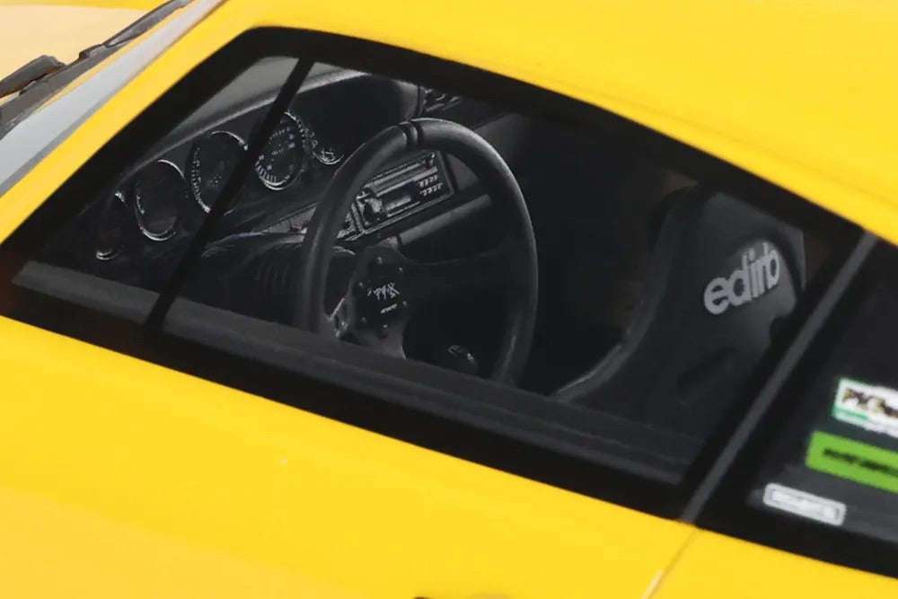 Yellow die-cast model car interior, black steering wheel and dashboard visible