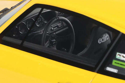 Yellow die-cast model car interior, black steering wheel and dashboard visible