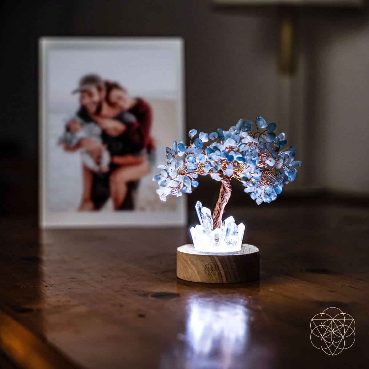 Aquamarine blue crystal tree lamp on round wood base on a wooden tabletop