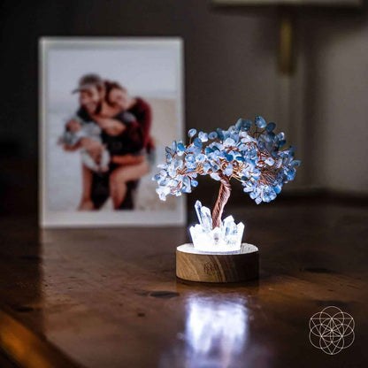 Aquamarine blue crystal tree lamp on round wood base on a wooden tabletop