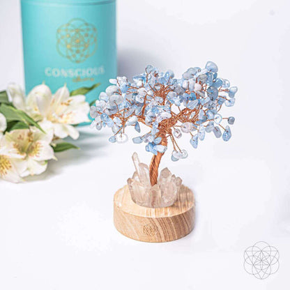 Aquamarine blue crystal tree lamp on round wood base with white rose quartz rocks