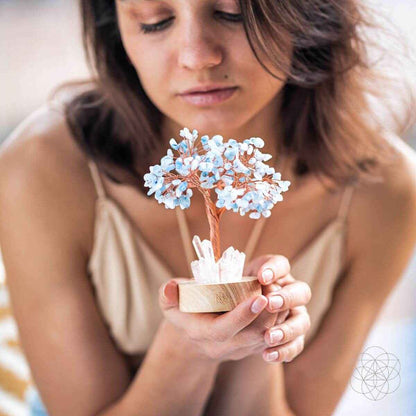Hand holding an aquamarine blue crystal tree lamp with white crystal stones on base
