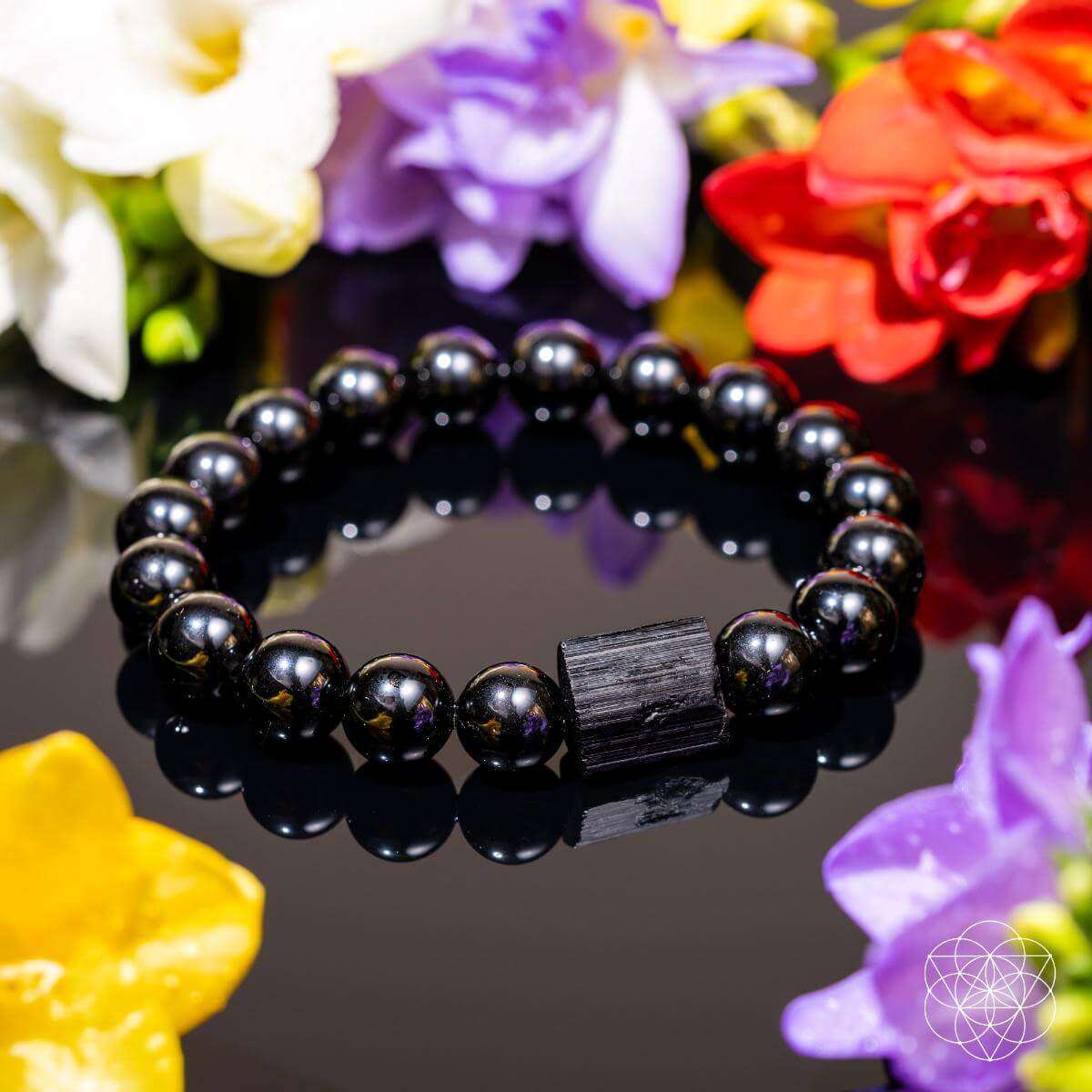 Black obsidian beaded bracelet with dark rectangular centerpiece among colorful flowers