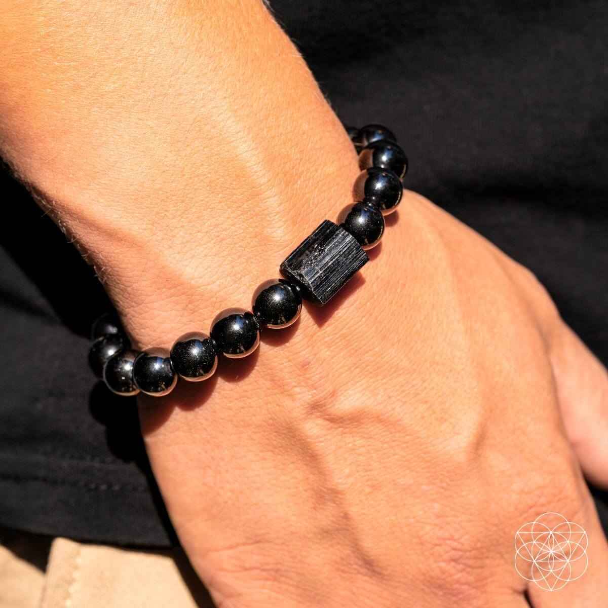 Black obsidian beaded bracelet with dark rectangular charm close to wrist