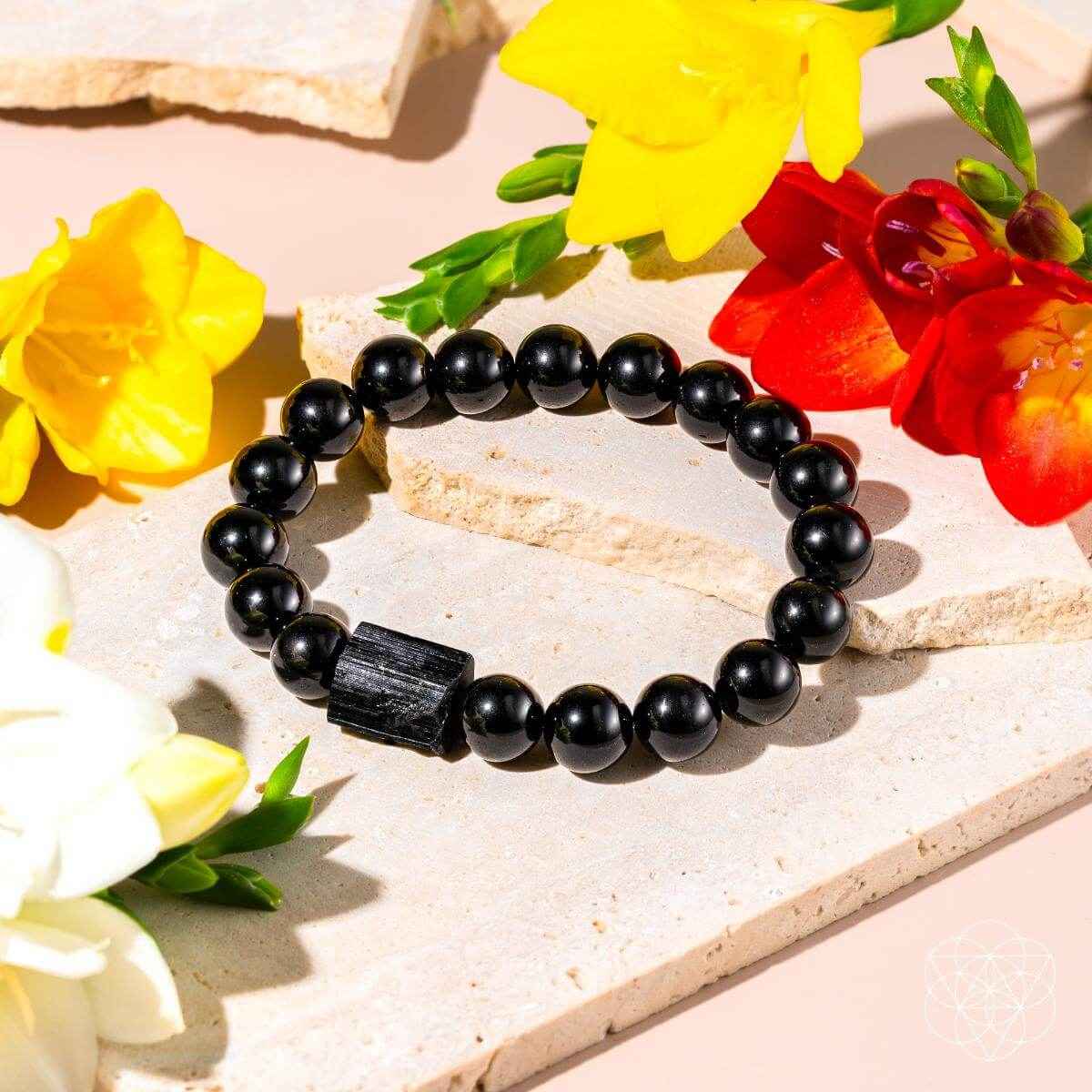 Black obsidian beaded bracelet with dark rectangular charm on stone