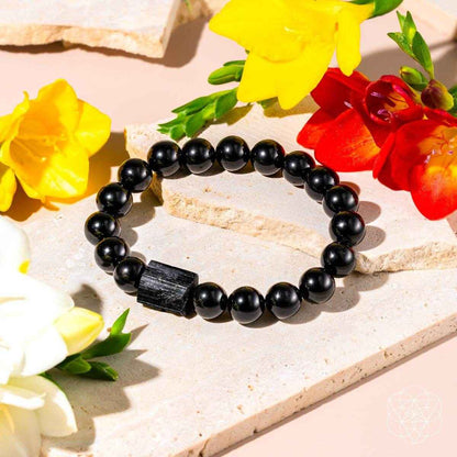 Black obsidian beaded bracelet with dark rectangular charm on stone