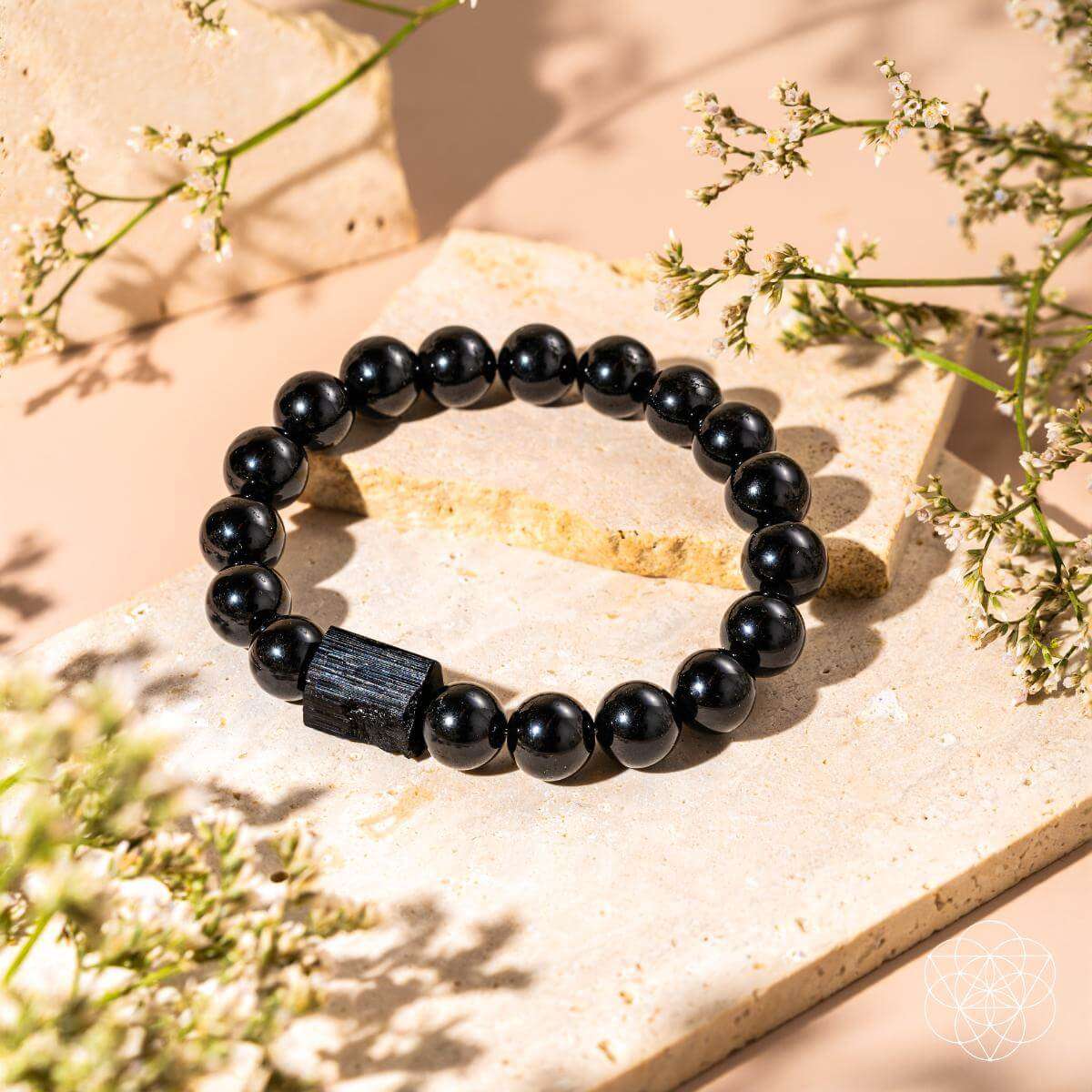 Black obsidian beaded bracelet with dark rectangular charm on light stone
