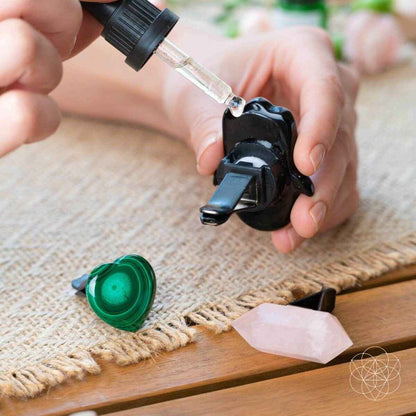 Black hamsa car diffuser with essential oil dropper, clipped in hands, green heart and rose quartz