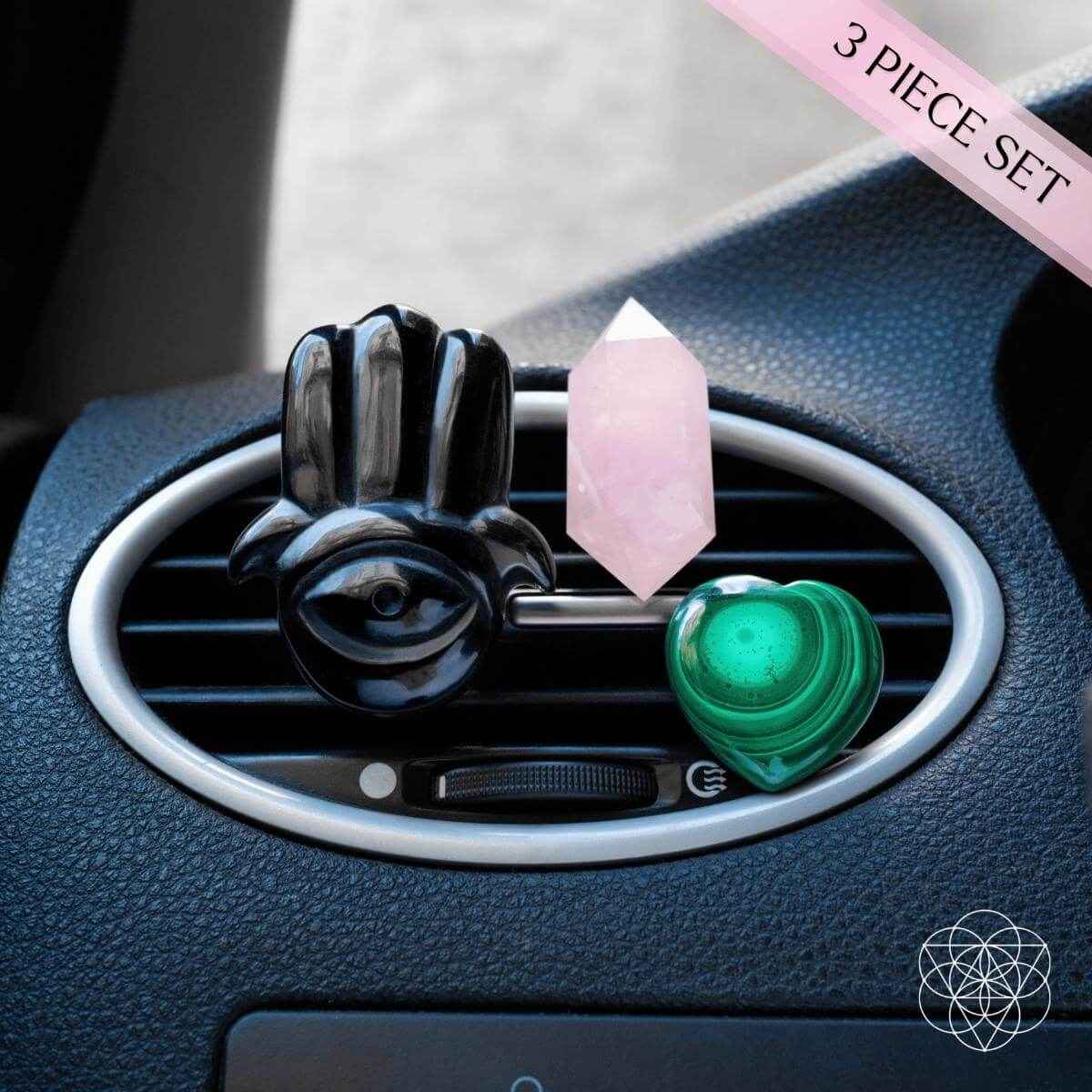 Black hamsa car diffuser clipped to vent with pink rose quartz point and green heart stone
