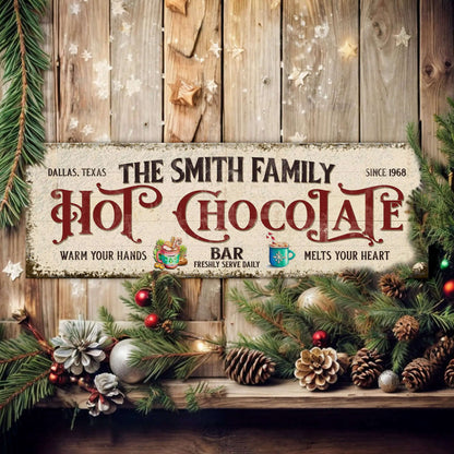 Holiday hot chocolate bar wall sign with greenery and pinecones on wooden boards