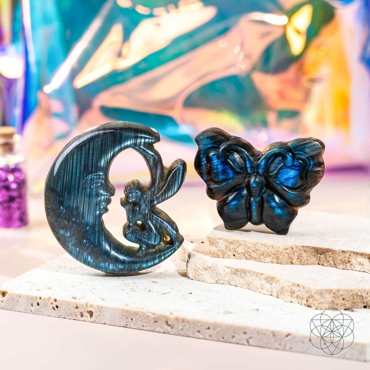 Blue labradorite moon and butterfly carvings placed on a stone ledge