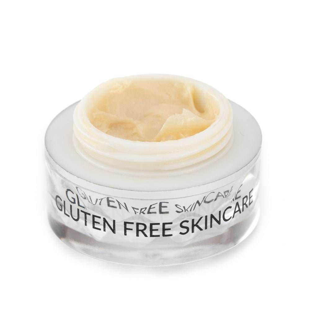 Eye cream jar with open lid and beige cream inside, clear faceted container