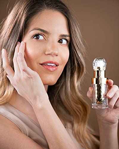 Woman holding a face serum bottle and applying serum to her cheek