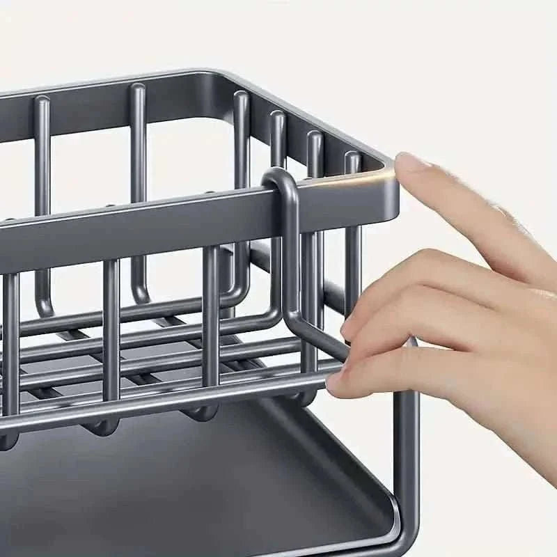 Gray sink storage rack with wire base and divider rails; hand adjusting front bar