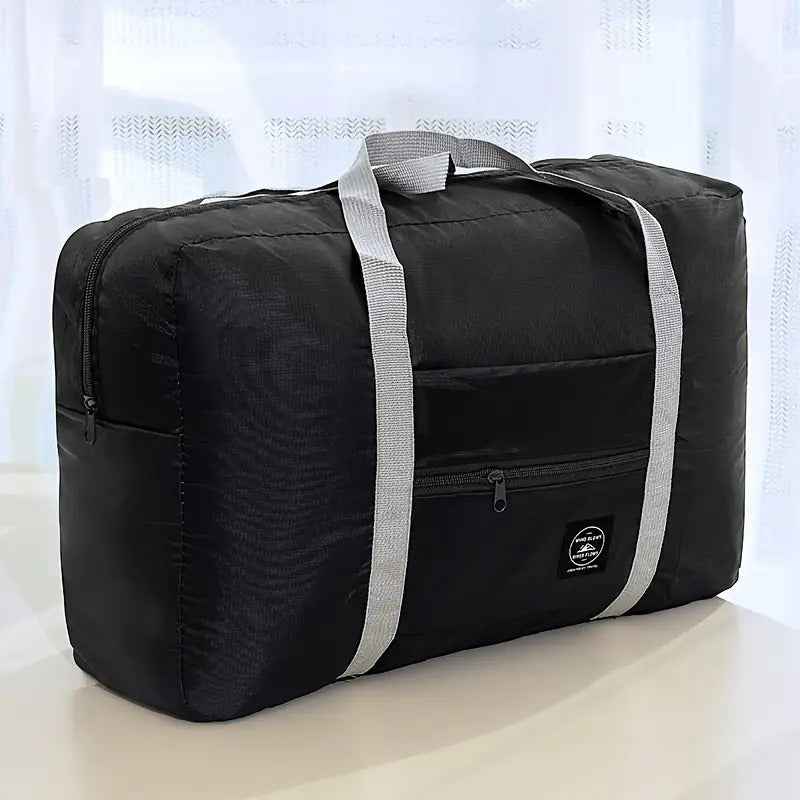 Black nylon duffel bag with front zip pocket, gray shoulder strap, logo patch