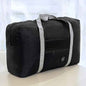 Black nylon duffel bag with front zip pocket, gray shoulder strap, logo patch