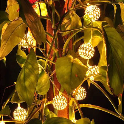 LED solar string lights with warm white globe bulbs woven through leaves