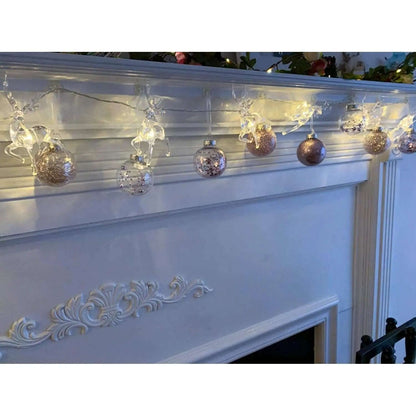 Warm white LED reindeer string lights hanging above a fireplace with glowing figures